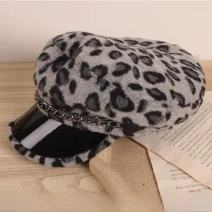 Détail d'une casquette enfant léopard avec chaîne en métal noir sur un support chic