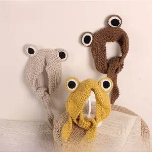 Detailed close-up of knitted frog headband in beige, brown and yellow yarn