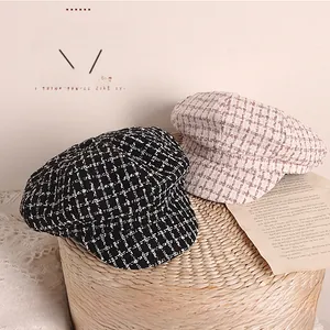 Dettaglio di berretti in tweed a quadri rosa e neri su un cesto di vimini intrecciato