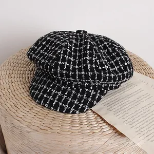 Dettaglio del berretto newsboy in tweed a scacchi bianco e nero su supporto intrecciato