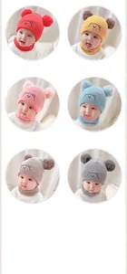 Detail view of baby knitted hat and scarf set with cute bear embroidery and double pom-poms