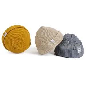 Detailed ribbed knit texture of kids beanies in yellow, beige and blue with smile patch
