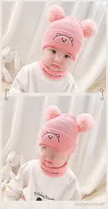 Detailed view of pink knitted baby hat and scarf set with cute bear embroidery and pom-poms