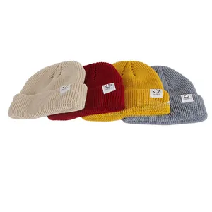 Detail view of colorful knitted beanies with smiley face patch in four assorted colors