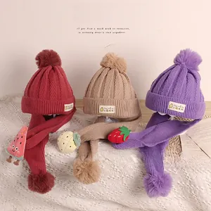 Détail de bonnets et écharpes en tricot avec pompons doux et breloques de fruits