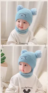 Close-up of baby blue knit hat and neck warmer set with cute bear embroidery and dual pom poms