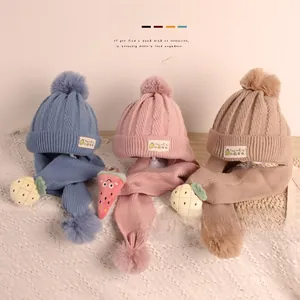 Détail d'un ensemble bonnet et écharpe tricotés pour enfants avec pompons