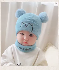 Detail of light blue knit baby hat with bear embroidery and matching neck warmer set