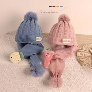 Détail de bonnets et écharpes tricotés pour bébé avec pompons et accents de fruits 3D