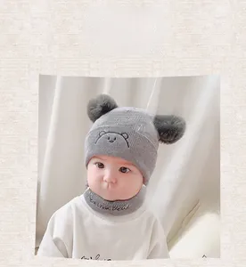 Close-up of baby winter knit hat and scarf set featuring cute bear embroidery and dual pom-poms