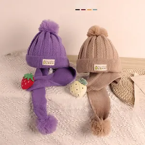 Détail de l'ensemble bonnet et écharpe en tricot pour bébé avec pompons et fraises