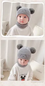 Detail of grey baby winter knit hat with cute bear embroidery and double pom-poms