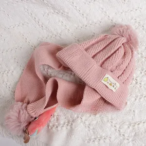 Détail de l'ensemble bonnet et écharpe en tricot rose avec pompon et écusson de fruit