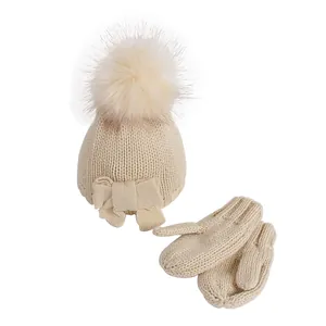 Infant winter knit hat and mittens set with fuzzy pompom and bow in beige color