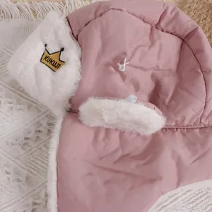 Detail of pink baby pilot hat featuring gold crown embroidery and soft plush lining