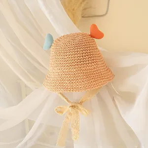 Detail of child straw sun hat featuring heart antennae and delicate lace chin straps