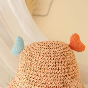 Detail of hand-woven straw sun hat for children with cute heart-shaped knitted antennas