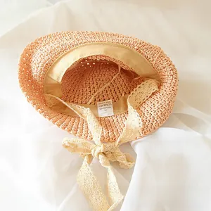 Detail of pink straw hat showing 100% paper texture, lace bow and size 48 label