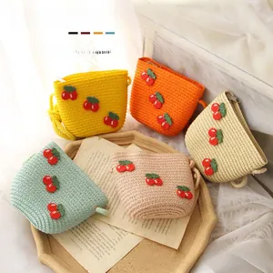 Detail of five handmade children's straw bags in assorted colors with cherry crochet decor