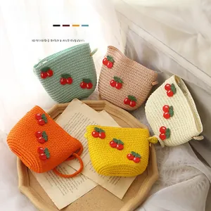 Detail of woven straw bags for kids with handmade red cherry crochet decorations