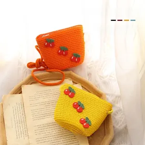 Detail of baby straw crossbody bags featuring cherry embroidery on soft woven material