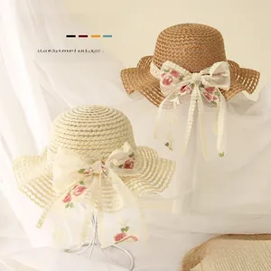 Détail de chapeaux de paille pour bébé avec nœuds en dentelle et broderies florales