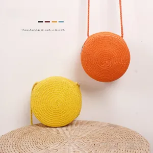 Détail de sacs ronds en paille tressée pour filles en jaune vif et orange