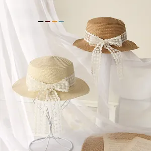 Détail de chapeaux de paille pour bébé avec nœuds en dentelle en crème et brun clair