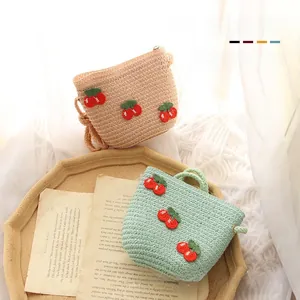 Close-up of woven straw bags in beige and mint green with red cherry embroidery detail