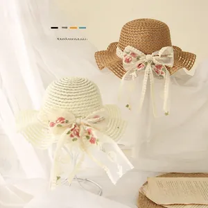 Détail de chapeaux de paille pour bébés avec grands nœuds en dentelle et broderie