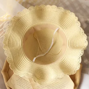Détail d'un chapeau de paille à bord ondulé, texture beige et mentonnière élastique