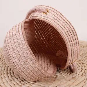 Détail macro du sac rond en paille tissée rose montrant la texture et la fermeture