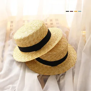 Close-up of kids straw boater hats with black ribbon on natural woven material