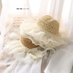 Detail of baby straw sun hat featuring elegant lace ruffled brim and ribbon bow decoration
