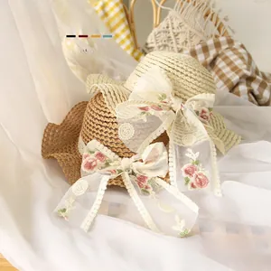 Détail de chapeaux en paille pour bébés avec nœuds en dentelle fleurie