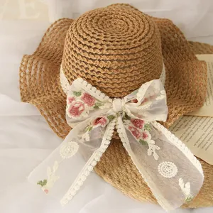 Détail d'un chapeau de paille pour filles avec ruban en dentelle et nœud floral rose