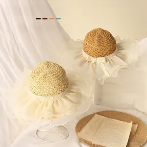 Detailed view of woven straw baby sun hat with delicate white lace ruffle and bow accent