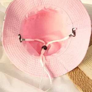 Détail intérieur d'un chapeau bob rose en coton avec sangle coupe-vent blanche réglable