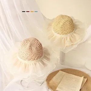 Detail of baby straw sun hats with wavy lace trim and elegant ribbons in beige colors