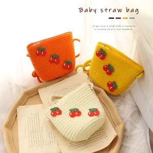 Three colors of kids cherry straw woven shoulder bags on vintage background