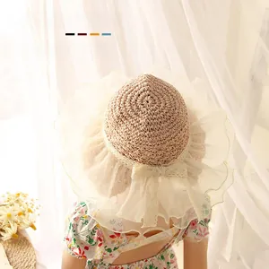 Detail of baby straw sun hat featuring elegant lace bow and soft ruffled tulle brim trim