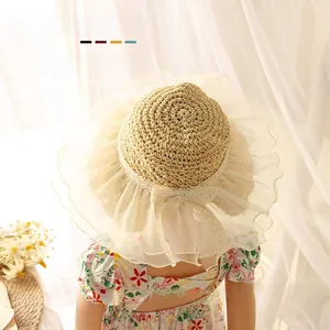 Detail of baby straw hat with delicate lace ruffles and bow in natural beige color