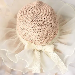 Detail of pink straw sun hat with white organza brim and lace bow decoration