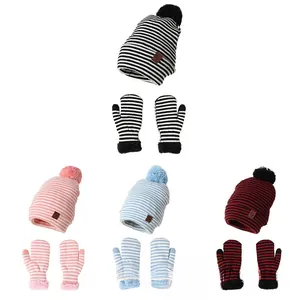 Detailansicht der gestreiften Kinder-Strickmütze mit Handschuhen, Bommel und Lederaufnäher