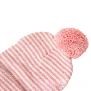 Detail der rosa-weiß gestreiften Strickmütze mit einem weichen flauschigen Bommel dekor
