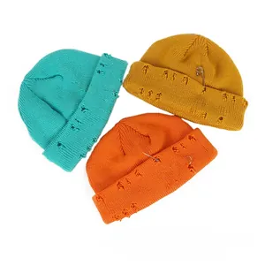 Detailed view of knitted beanies with silver rings and safety pin distress decorations