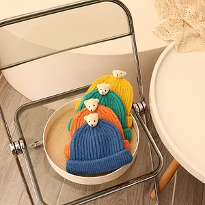 Vier farbenfrohe Strickmützen mit süßen 3D-Bären-Dekorationen in der Nahaufnahme