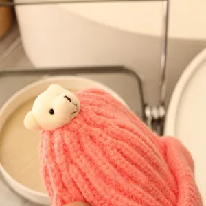 Detail einer rosa Strickmütze für Kinder mit kleinem Plüschbären als Winteraccessoire