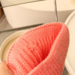 Makroaufnahme einer korallenrosa Strickmütze mit weicher Rippstruktur und Wollmaterial