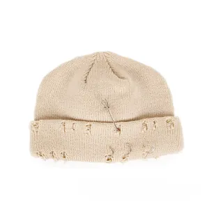 Close-up of beige distressed knit beanie with silver safety pin and triple metal rings